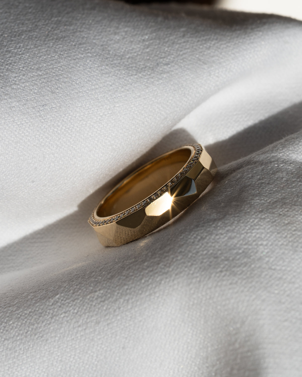 Faceted hammered gold wedding band with pavé side diamonds, modern geometric design
Wide yellow gold wedding band with angular hammered texture and diamond edge detailing
Contemporary gold men’s wedding band with faceted finish and subtle diamond accents
