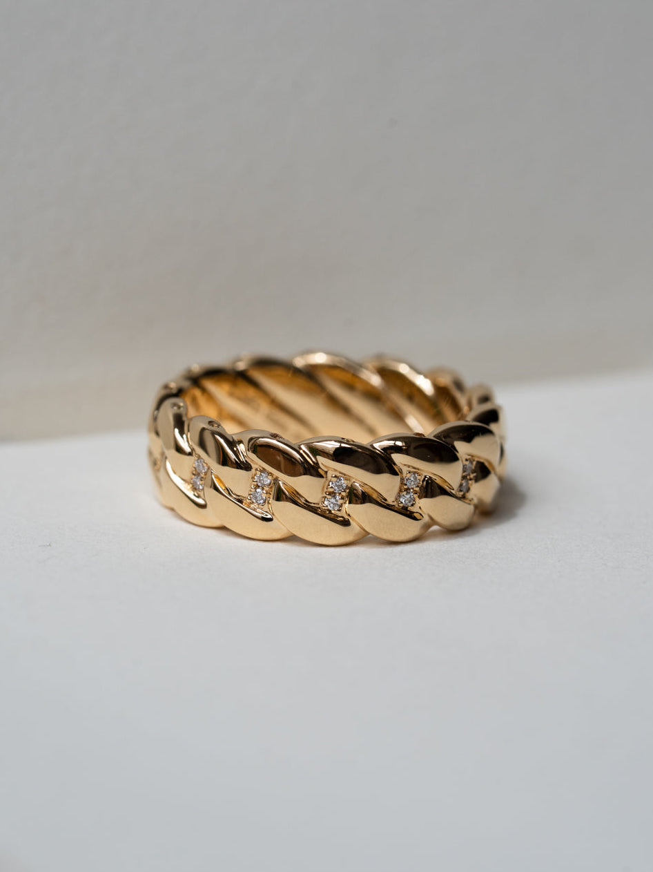 Custom Cuban link chain engagement ring in 18ct yellow gold with pavé diamonds set between links, top view on grey background