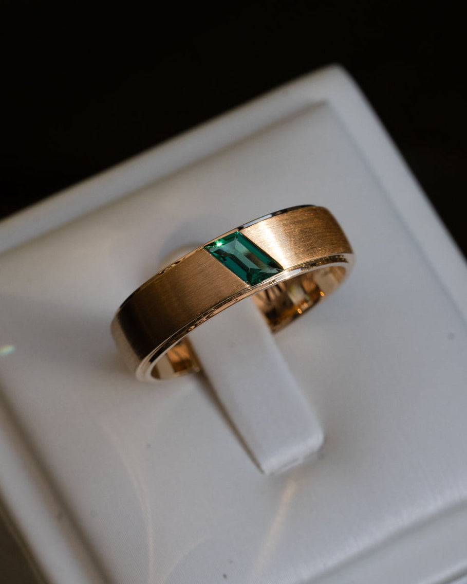 Brushed 18k gold wedding band with custom parallelogram emerald centre stone