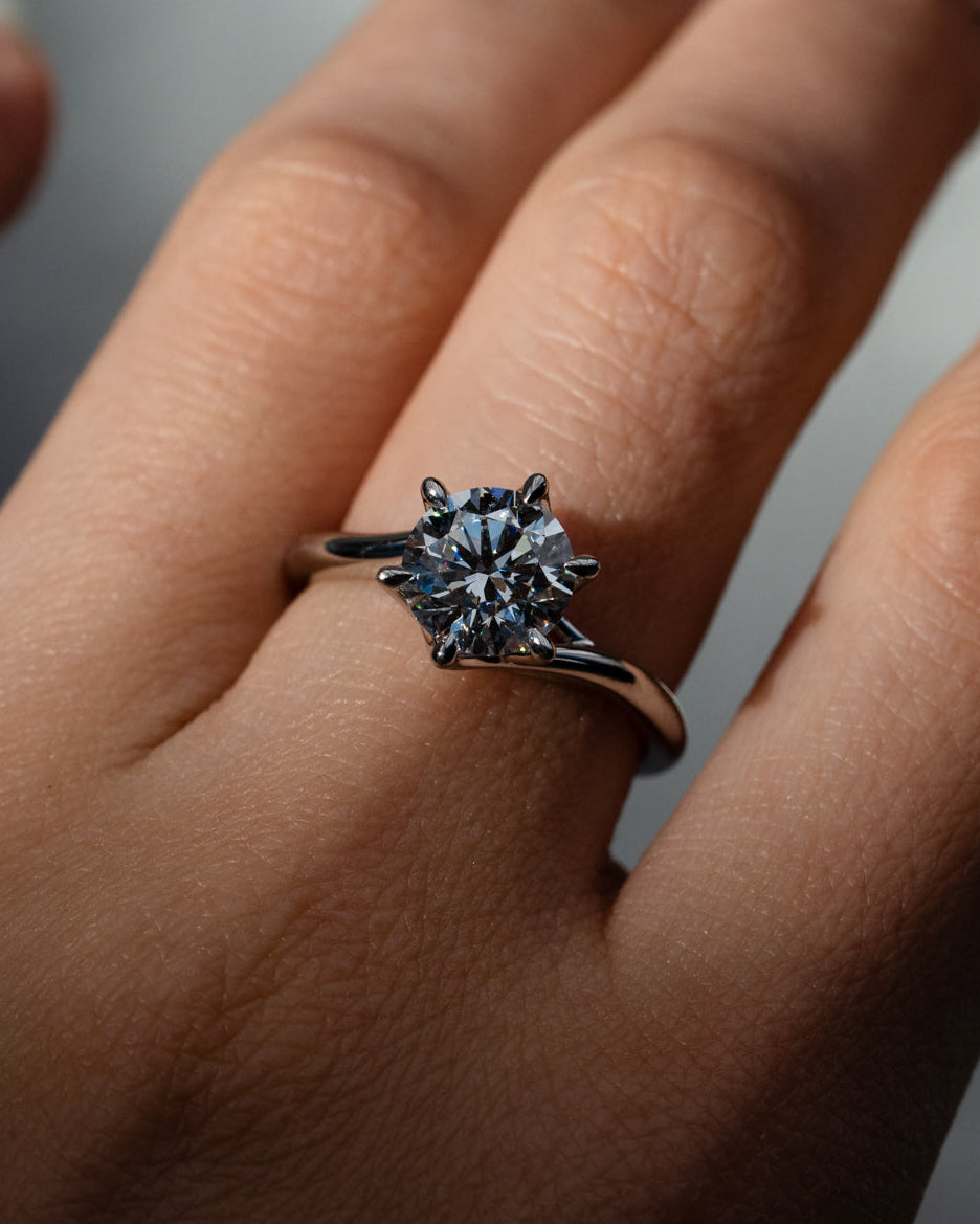 Close-up of a hand wearing a diamond ring with a blurred background