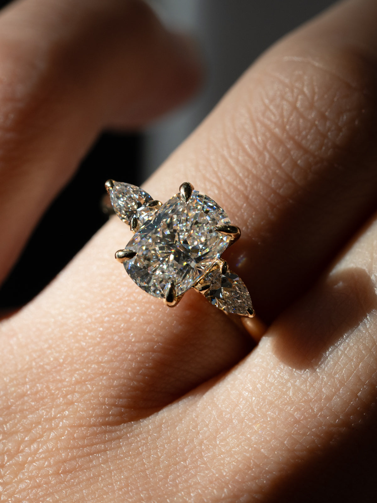 Custom elongated cushion cut diamond engagement ring with natural pear side stones in 18k yellow gold trilogy setting with floral basket and eagle prongs - bespoke engagement ring