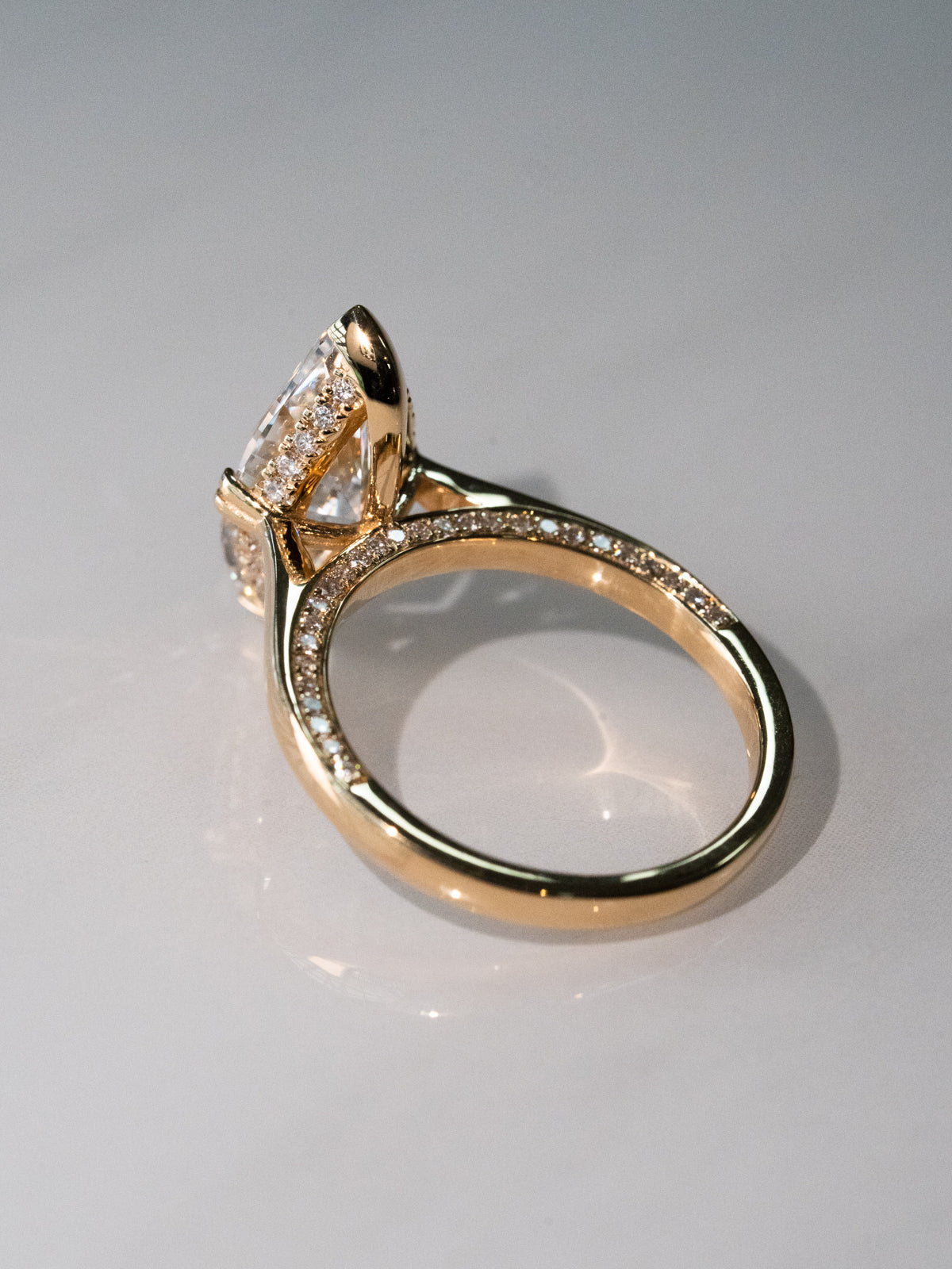 Side view of marquise diamond engagement ring showing cathedral setting and pavé diamond band in yellow gold