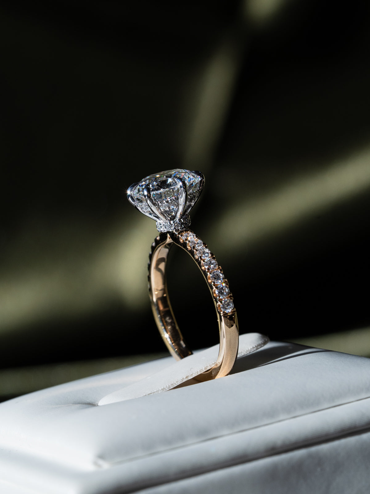 Close-up of round brilliant cut diamond solitaire engagement ring showing platinum setting and pavé diamonds